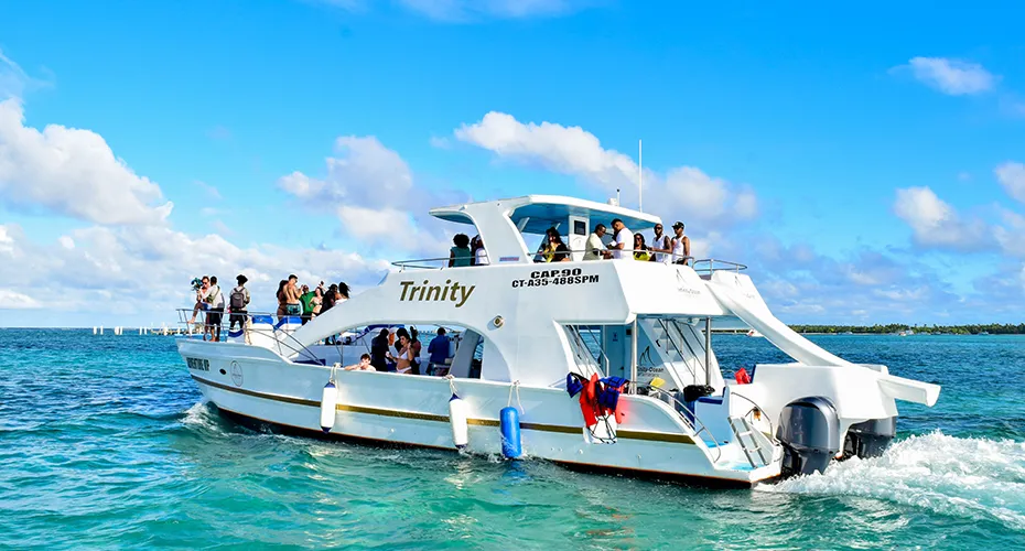 Party boat named 'Trinity' cruising through blue waters with passengers enjoying the ride on a sunny day.