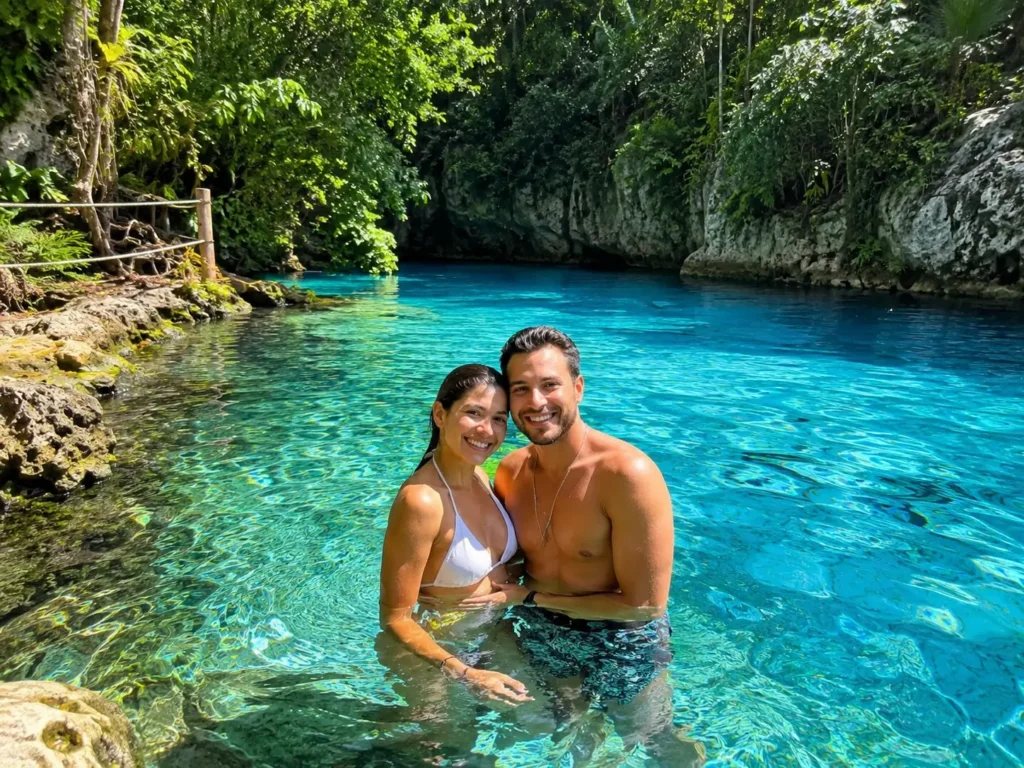 Couple swimming in the clear blue waters of Hoyo Azul Cenote in Punta Cana, surrounded by tropical greenery and natural limestone cliffs.