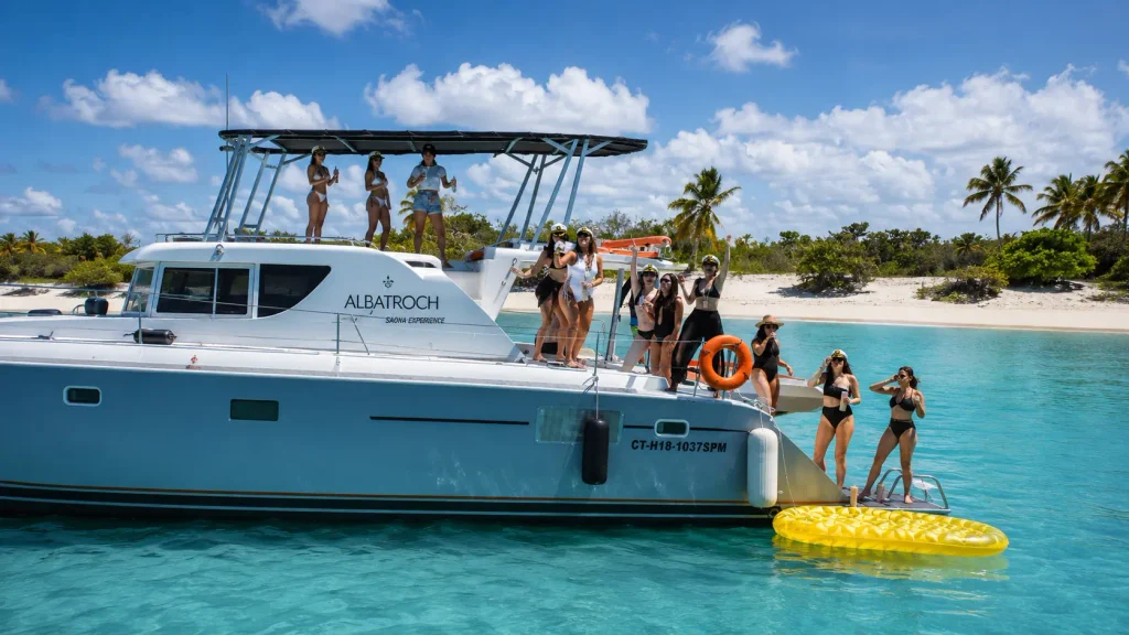 Group enjoying a catamaran boat trip in Punta Cana on clear turquoise water near a tropical beach.