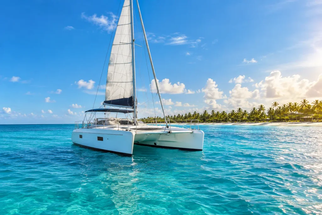 White catamaran cruising through calm turquoise Caribbean waters in Punta Cana during June, illustrating Punta Cana Weather in June.