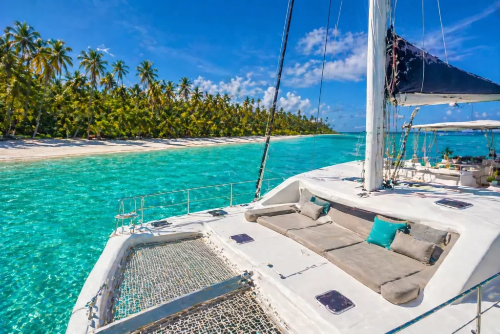Luxury catamaran deck view sailing near Saona Island with turquoise water and palm-lined beach in the Caribbean