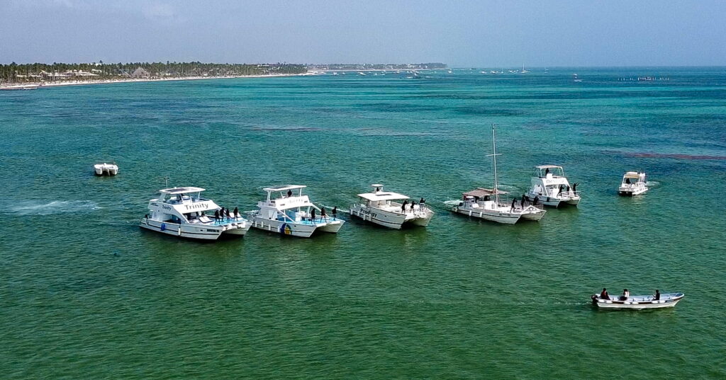 Catamarans sailing in the ocean near Punta Cana with clear blue water and tropical Caribbean coastline