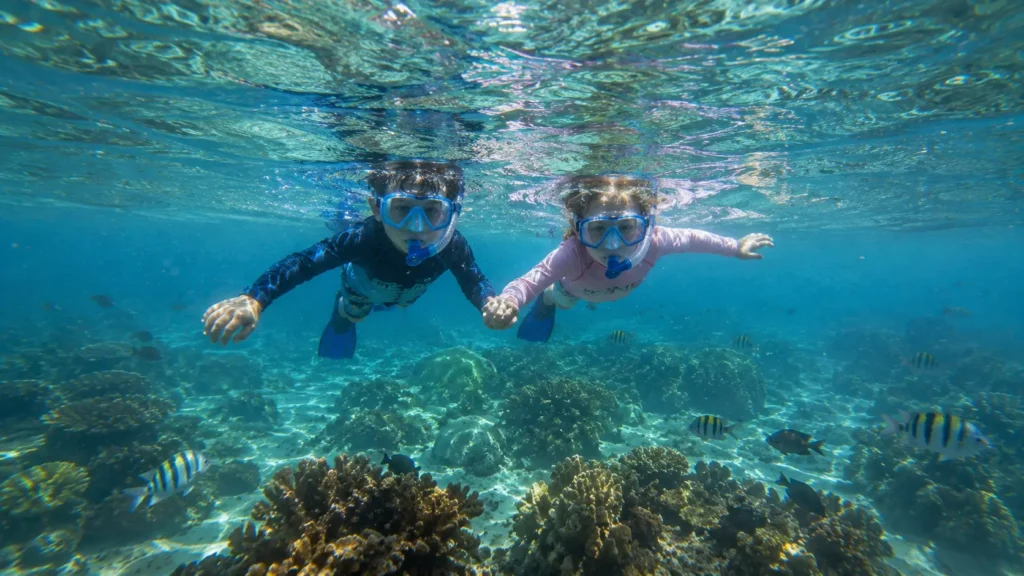 Kids snorkeling in the clear waters of Punta Cana while exploring a colorful coral reef and tropical fish during a family-friendly snorkeling excursion.
