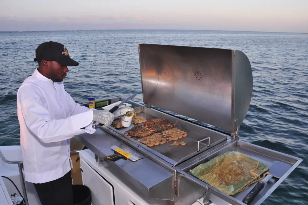 Chef grilling fresh seafood on a catamaran in Punta Cana with stunning Caribbean ocean views.