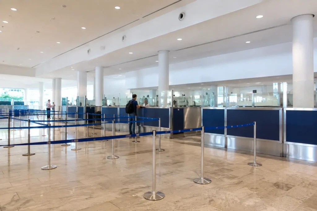 Travelers completing immigration at Punta Cana Airport with passport control counters and organized queue barriers inside a modern airport arrivals hall.
